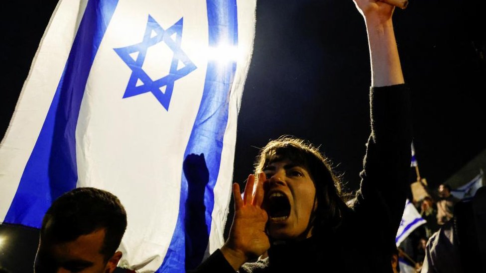A woman yells while holding an Israeli flag