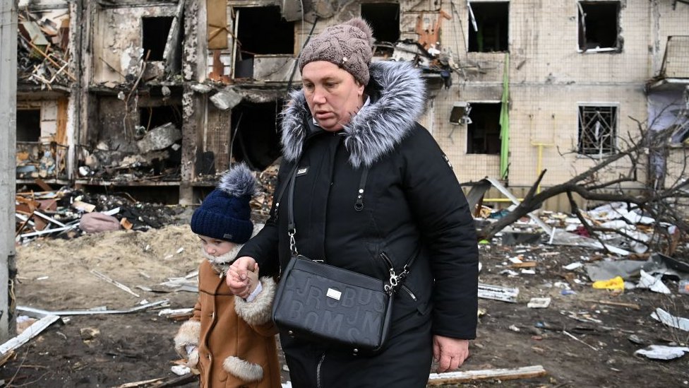 Una mujer y una niña escapan de un edificio dañado por un misil en Kiev.