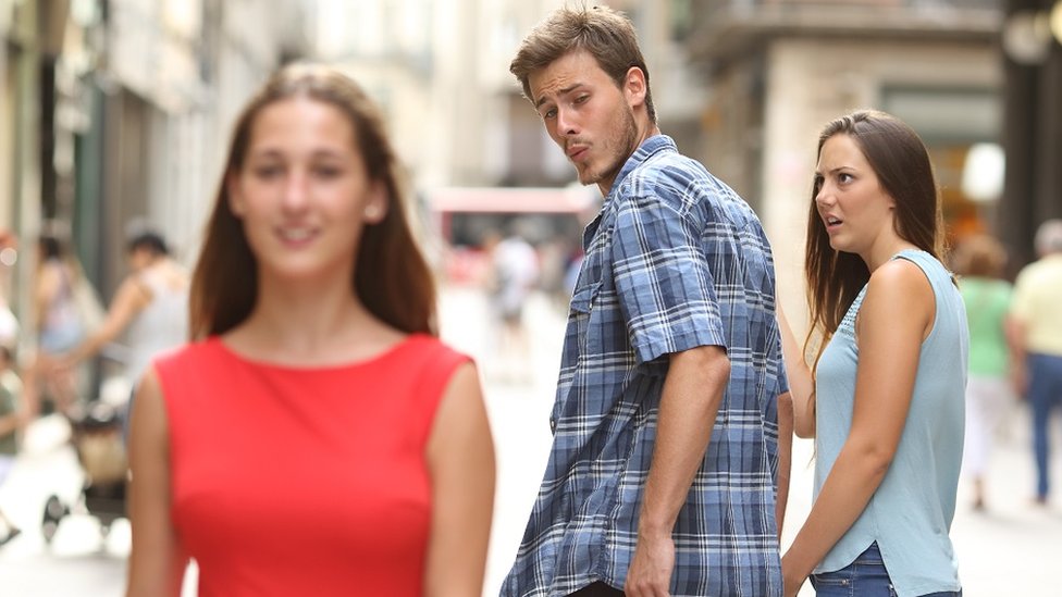 Disloyal man walking with his girlfriend and looking amazed at another girl