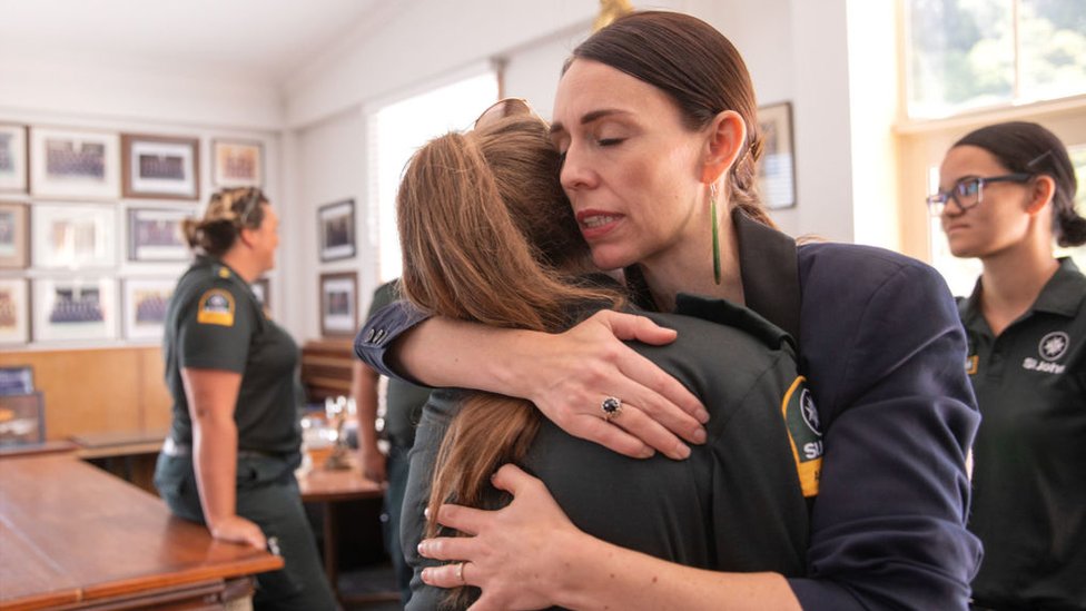 La primera ministra de Nueva Zelanda, Jacinda Ardern, abraza a mujer miembro del equipo de emergencias.