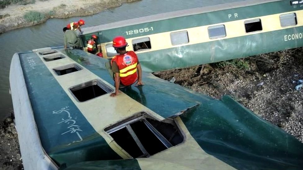 巴基斯坦信德省納瓦布沙阿客運火車出軌事故現場救援人員在扭曲的巴基被甩車廂殘骸中攀爬（6/8/2023）