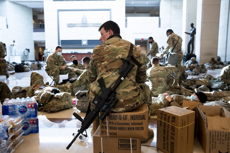 Soldiers sit inside of visitors area, sitting on supplies including water bottles