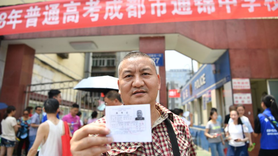 Liang Shi holds his ID up in front of a 2018 National College Entrance Examination building on 07 June, 2018 in Chengdu, Sichuan, China.