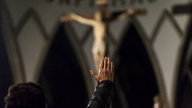 Hombre frente a Cristo levantando la mano
