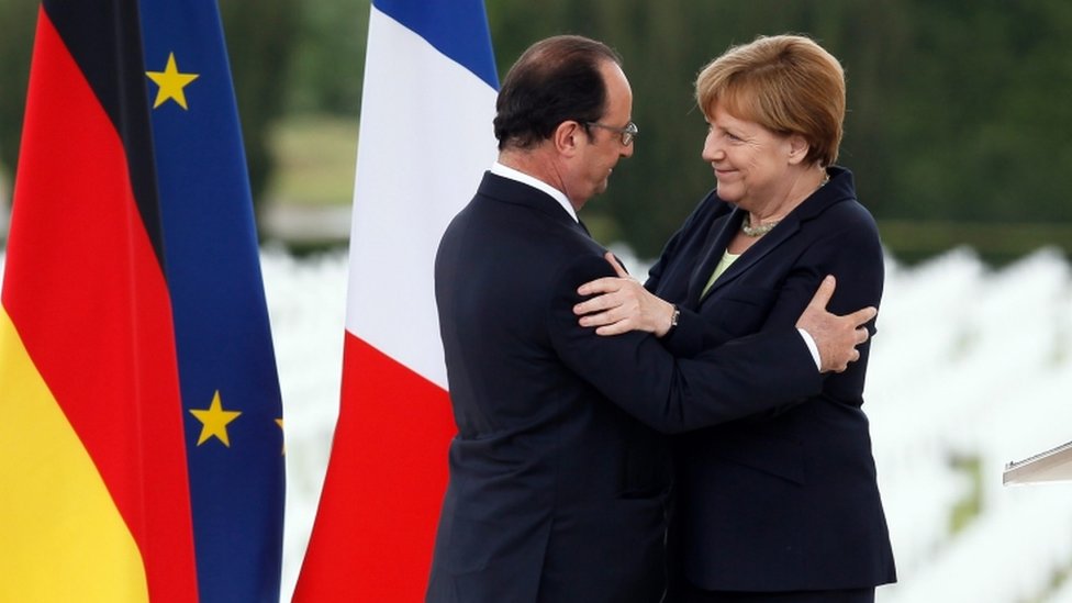 Президент Франции Франсуа Олланд (слева) приветствует канцлера Германии Ангелу Меркель (справа) после выступления с речью по случаю столетия битвы при Вердене