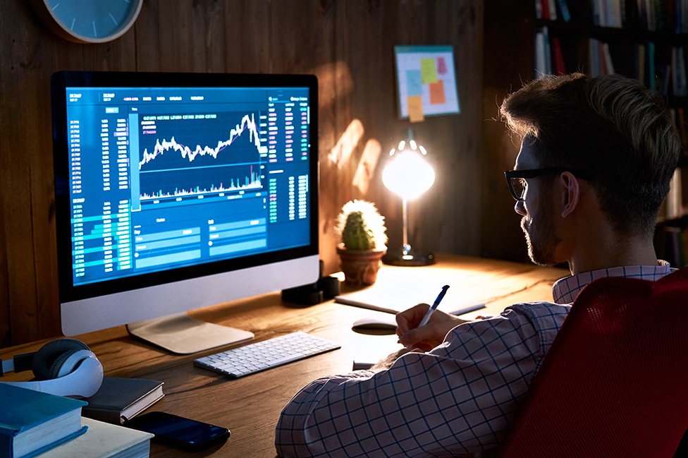 Un hombre joven mirando un gráfico financiero en su computadora