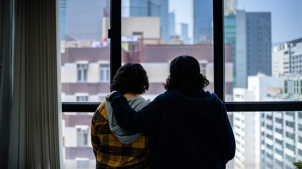 Las hermanas sauditas miran a través de la ventana de su hotel en Hong Kong