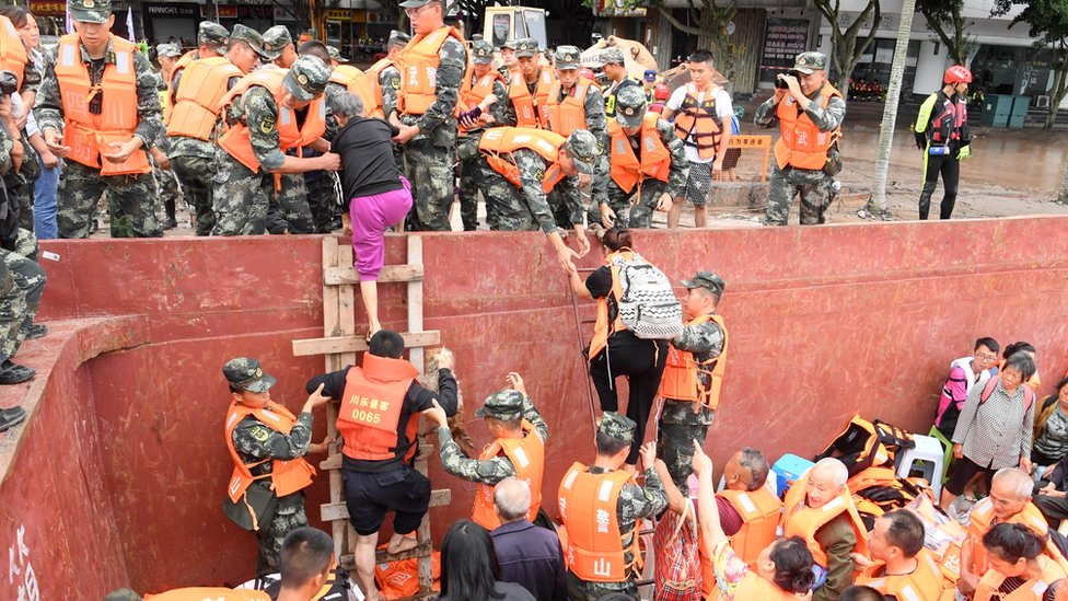 Rescuers help evacuated villagers get off boats onto land in Sichuan (18 August)