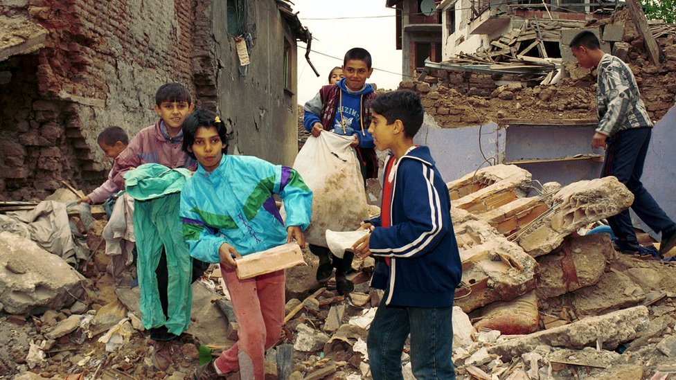 Дети несут обломки разрушенного в результате нападения дома