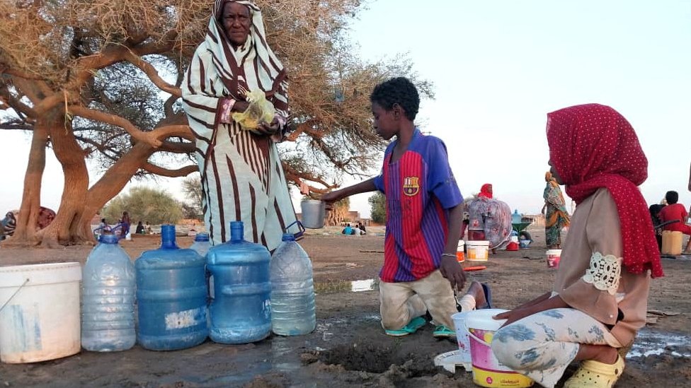 طفلين وسيدة عجوز بجانب قوارير من مياه الشرب