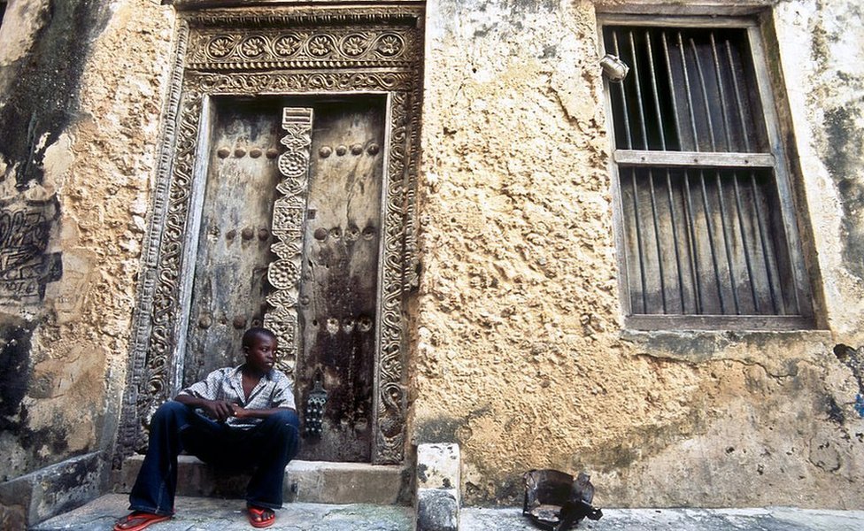 A boy sits in front of a house in Lamu town.