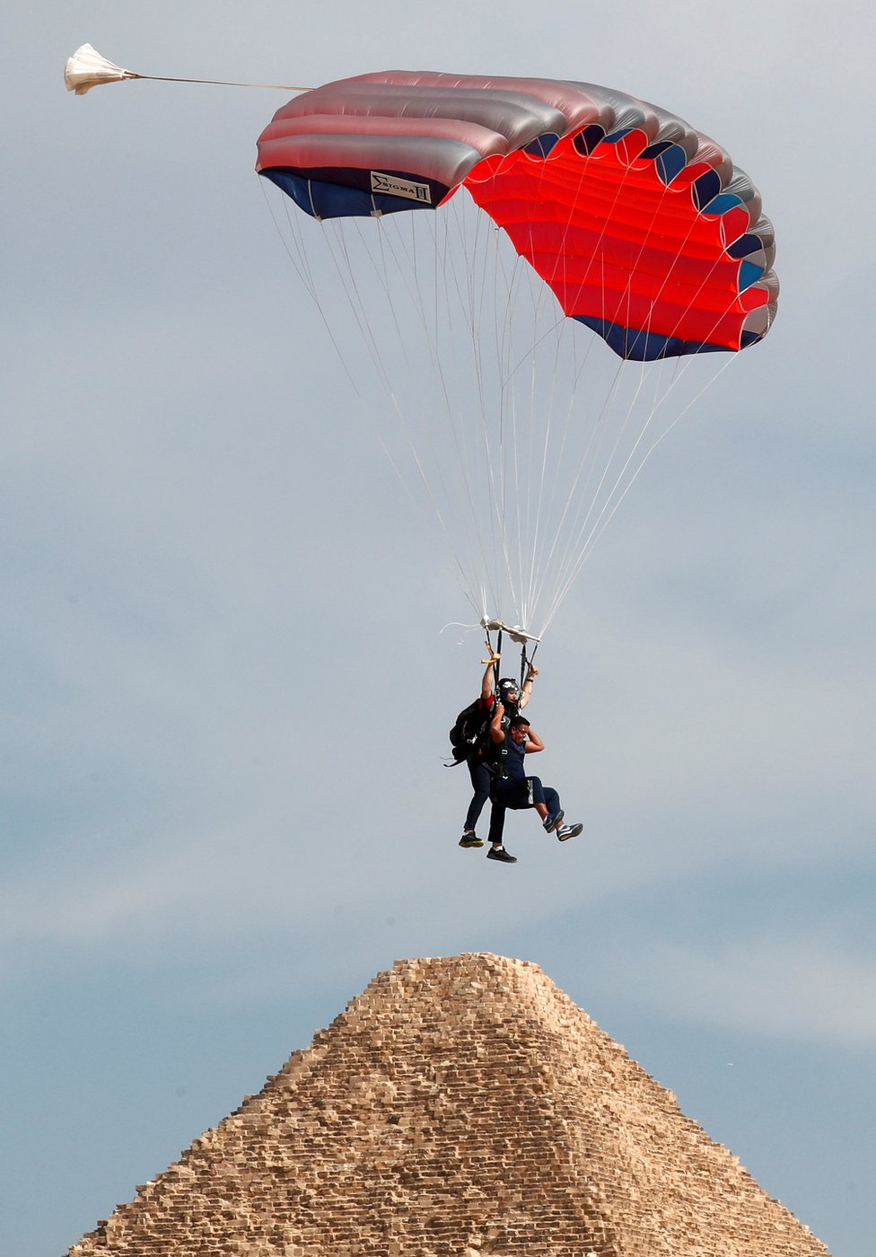 A professional skydiver carries a tourist as they fly over pyramid Khufu or "Cheops".