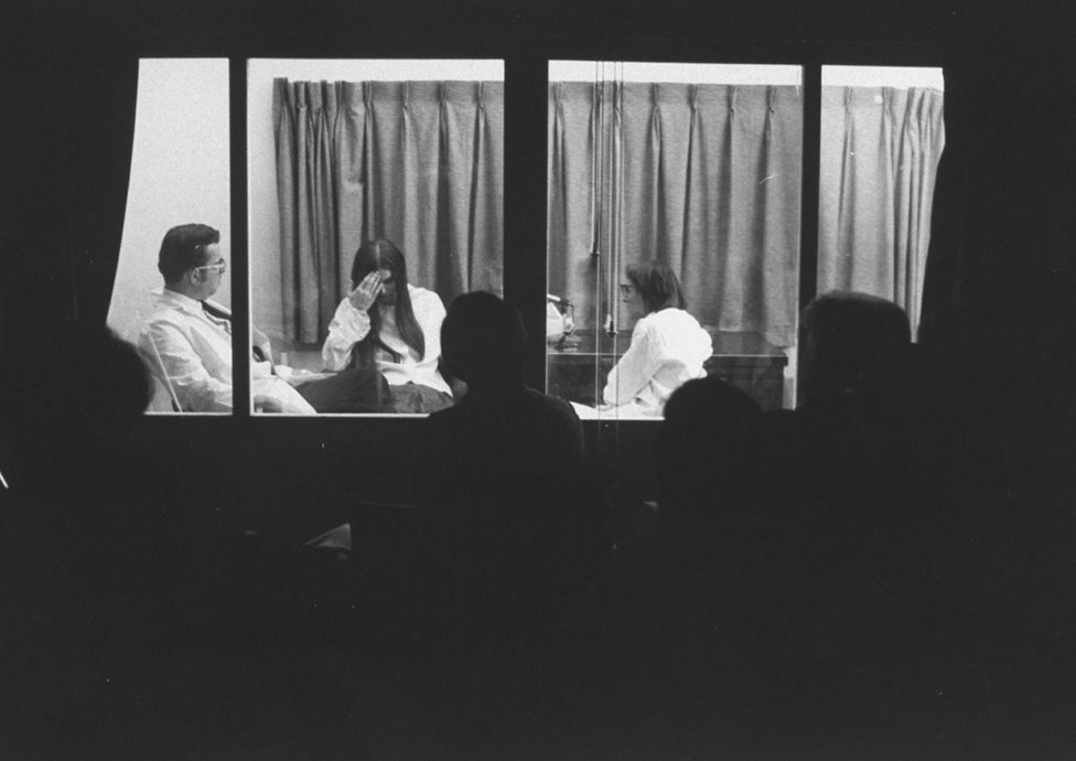 Элизабет Кюблер-Росс берет интервью у женщины, больной лейкемией, в Чикаго в 1969 году, участники семинара сидят за односторонним зеркалом