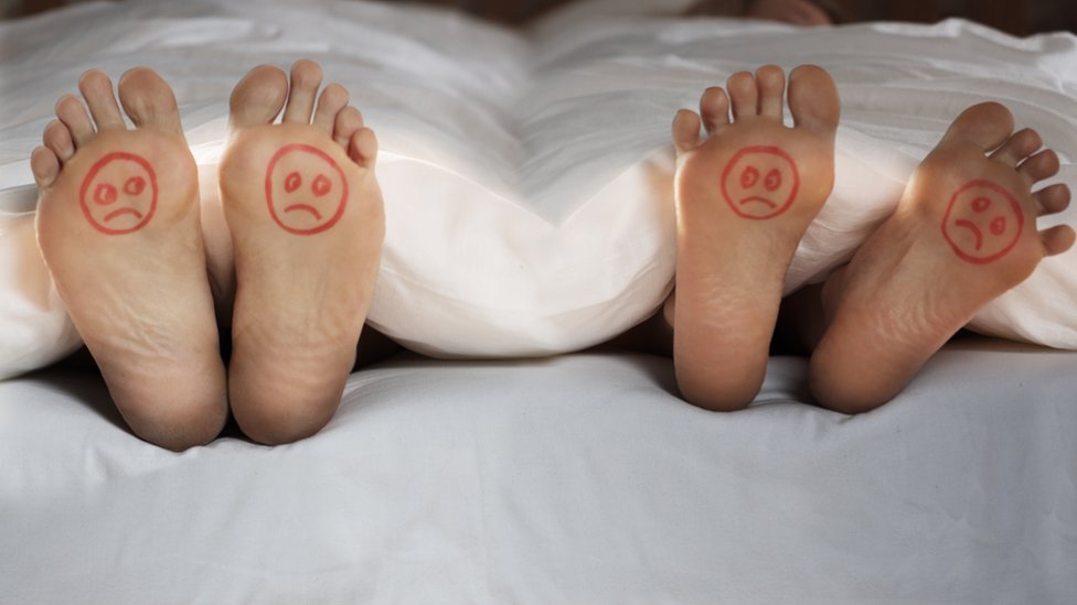 Image of feet with drawings of unhappy faces.