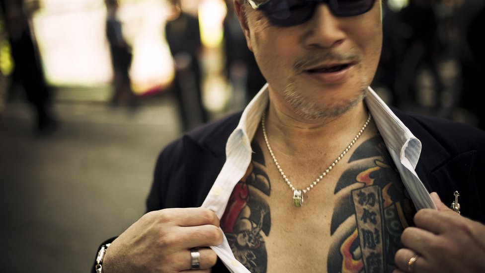 Un hombre mostrando sus tatuajes