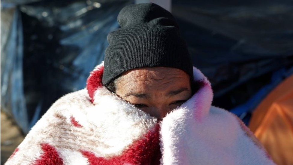 A Mexican migrant covers her face with a blanket as she and others camp at a park while waiting to apply for asylum in the US, in Ciudad Juarez on 17 December, 2019,
