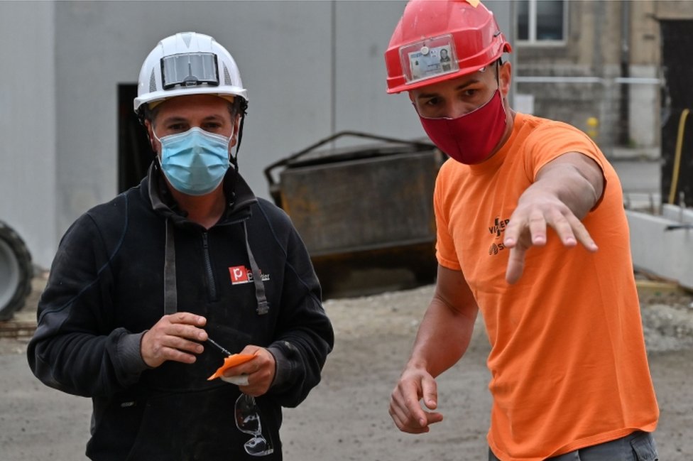Строители в защитных масках работают 28 апреля 2020 года на строительной площадке парковки в Шамбери, на востоке Франции