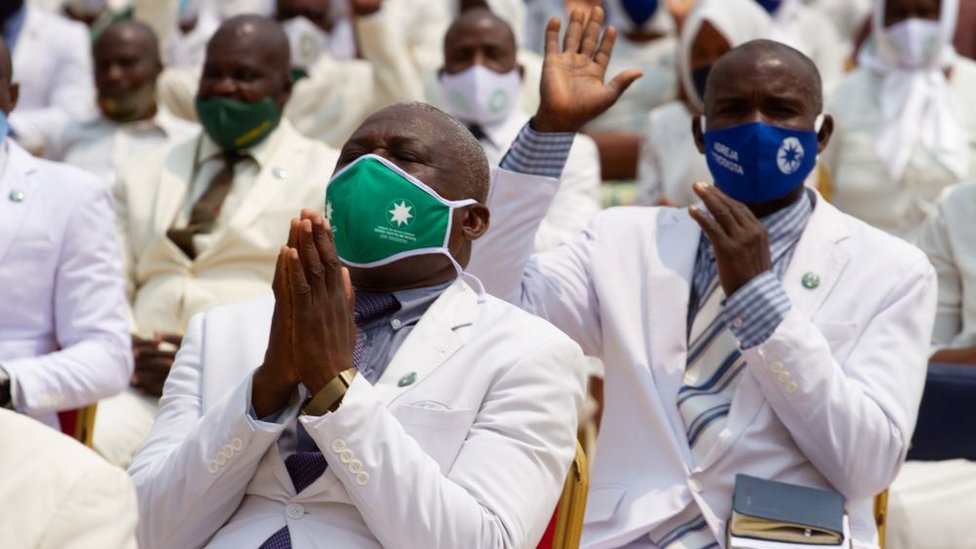 Members of the congregation raise their hands in prayer at the Church of Our Lord Jesus Christ In the World, in Luanda on September 20, 2020.