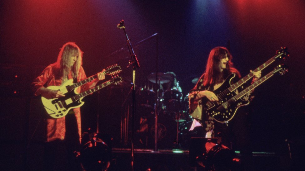 Канадская рок-группа Rush выходит на сцену во главе с гитаристом Алексом Лифсоном (слева) с певцом и басистом Гедди Ли