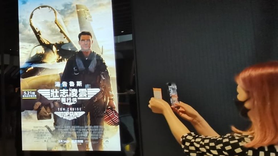 香港一家電影院門口一位女性觀眾在拍攝"《壯志凌雲：獨行俠》的招貼畫