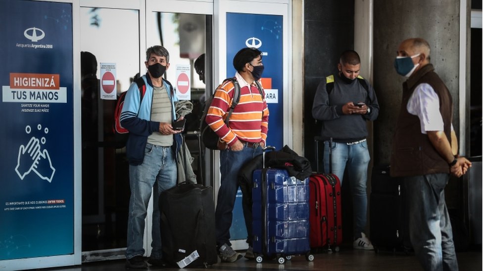 Três passageiros e um segurança do lado de fora de aeroporto