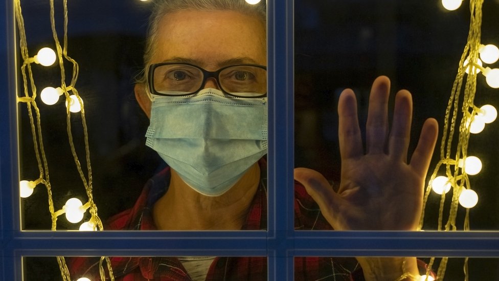 Man indoors looking out at dark evening