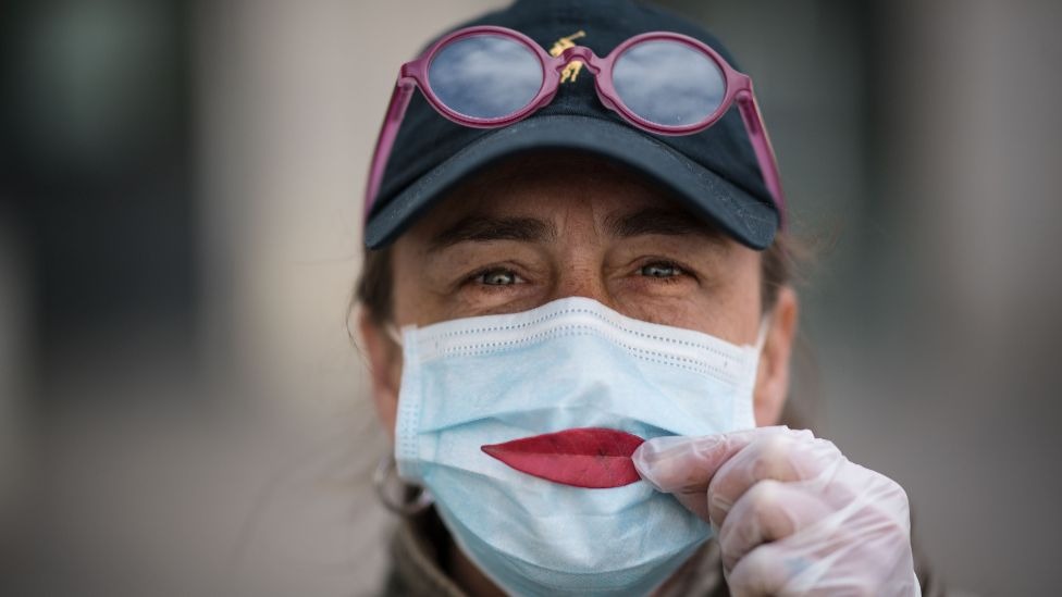 A woman wearing a protective mask holds a leaf as a smile in France, on 29 March 2020