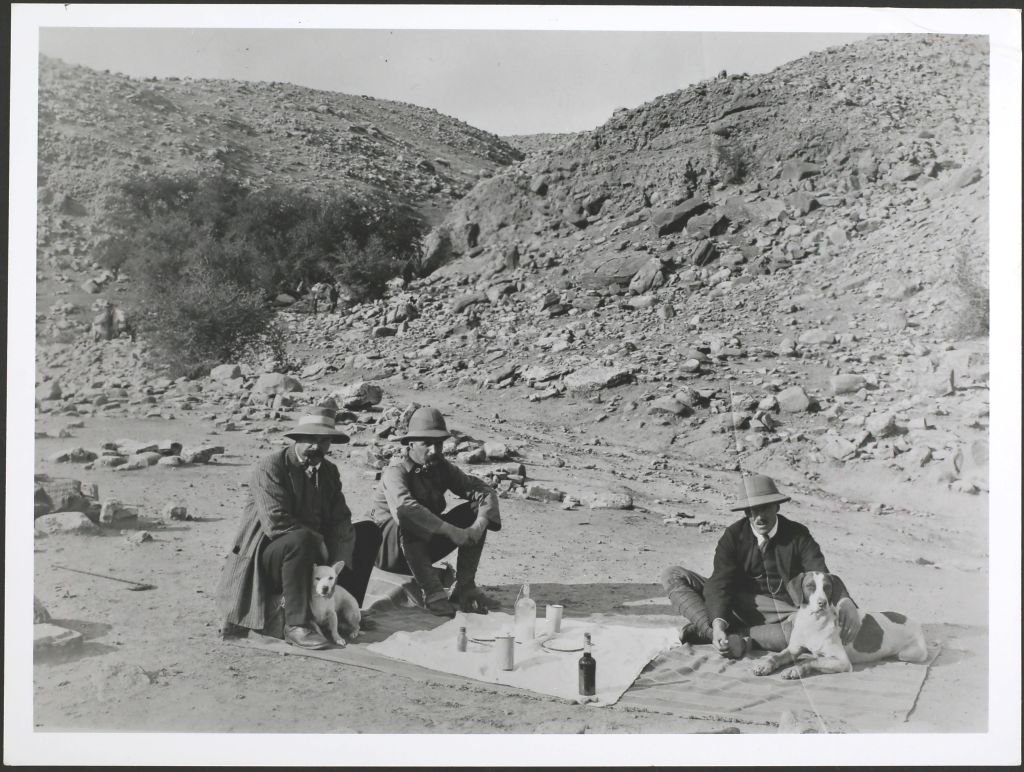 El pionero de la minería petrolera George Bernard Reynolds (izquierda), quien perforó el primer pozo con éxito, con Williams y otro asistente en un pícnic cerca de Masjid i-Suleiman en Persia (Irán) con sus perros a comienzos del siglo XX.