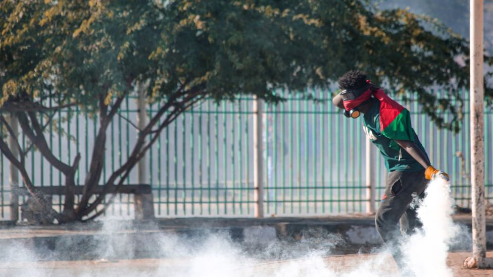 متظاهر يحمل قنبلة مسيلة للدموع أمام القصر الرئاسي في الخرطوم، السودان