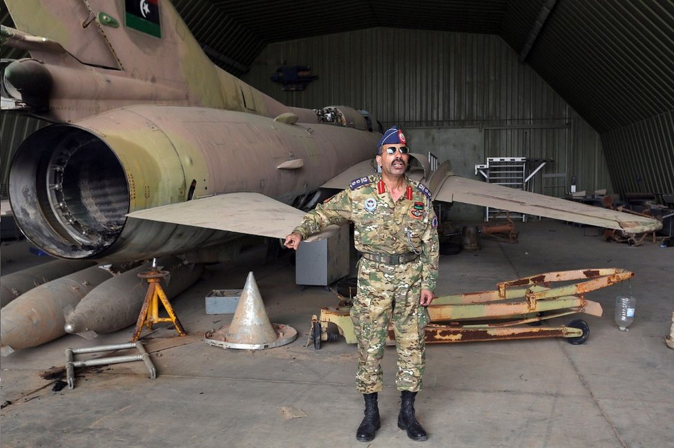 المتحدث باسم قوات الحكومة محمد قنونو بجوار طائرة من طراز ميغ-23 في قاعدة الوطية