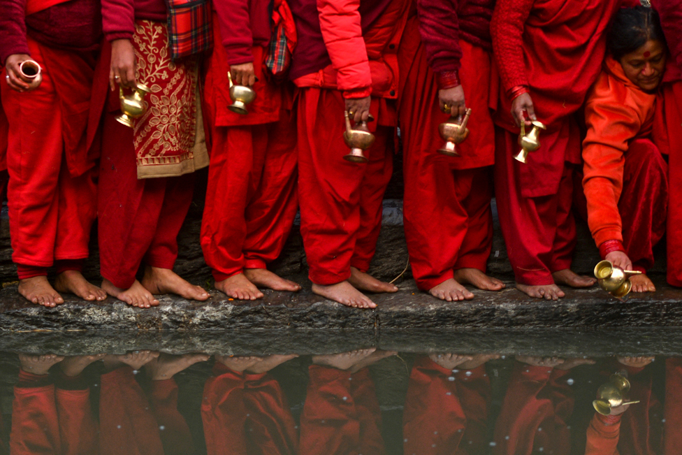 مواطنون يصطفون لملء الأواني بالمياه من نهر باجماتي المقدس في معبد باشوباتيناث في كاتماندو عاصمة نيبال، خلال مهرجان سواثاني براتا كاتا الهندوسي الذي يستمر لمدة شهر.