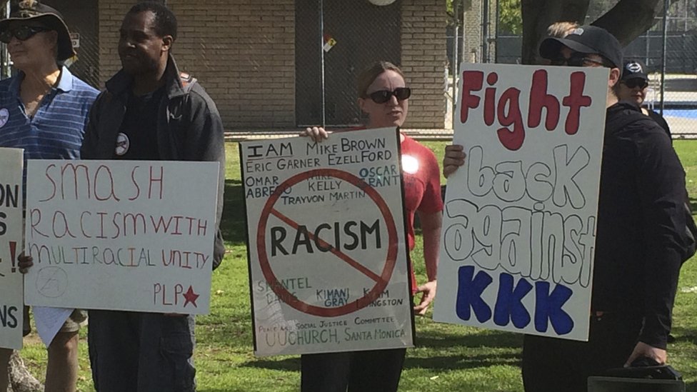 Встречные протестующие держат плакаты возле запланированного митинга Клу-клукс-клана в Анахайме, Калифорния, 27 февраля 2016 г.