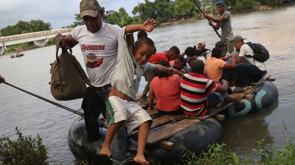 Una balsa repleta de migrantes cruza el río que funciona como un límite natural entre Guatemala y México.