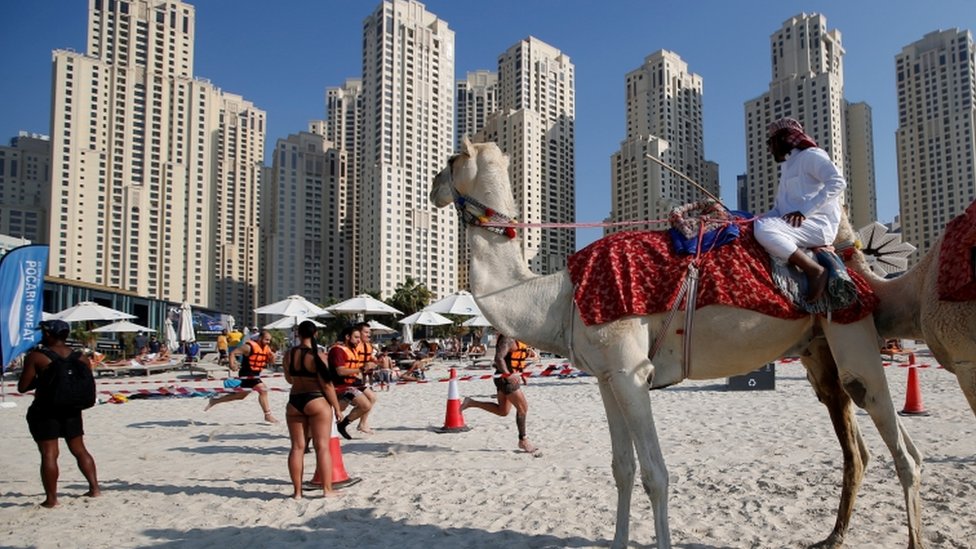 A spectator on a camel watches participants competing during the Aqua Challenge sports event in Gulf emirate of Dubai, United Arab Emirates