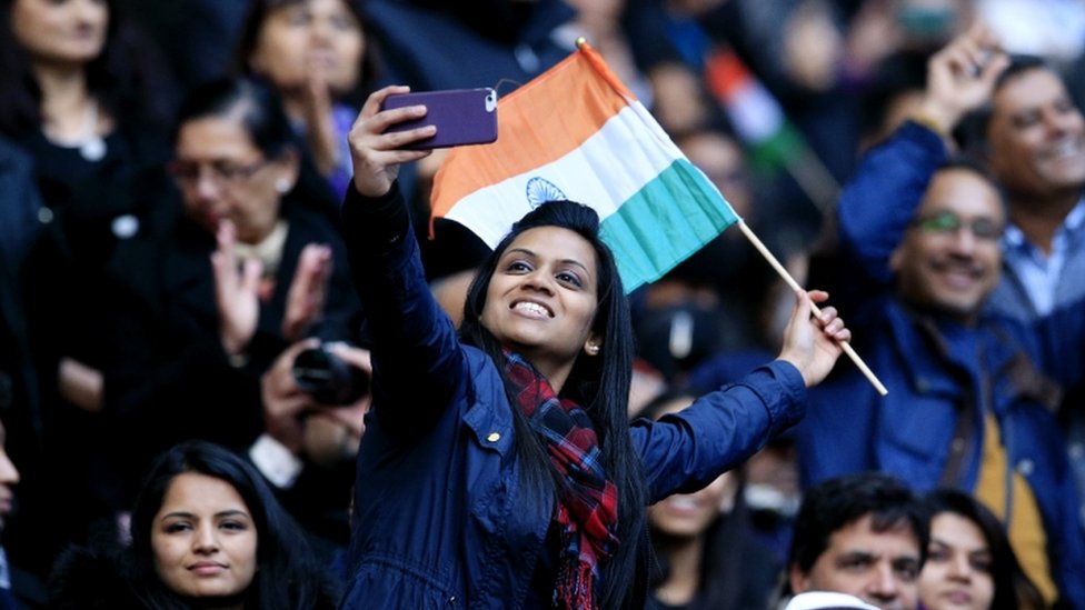 Женщина делает «селфи» на свой телефон среди толпы на стадионе «Уэмбли»