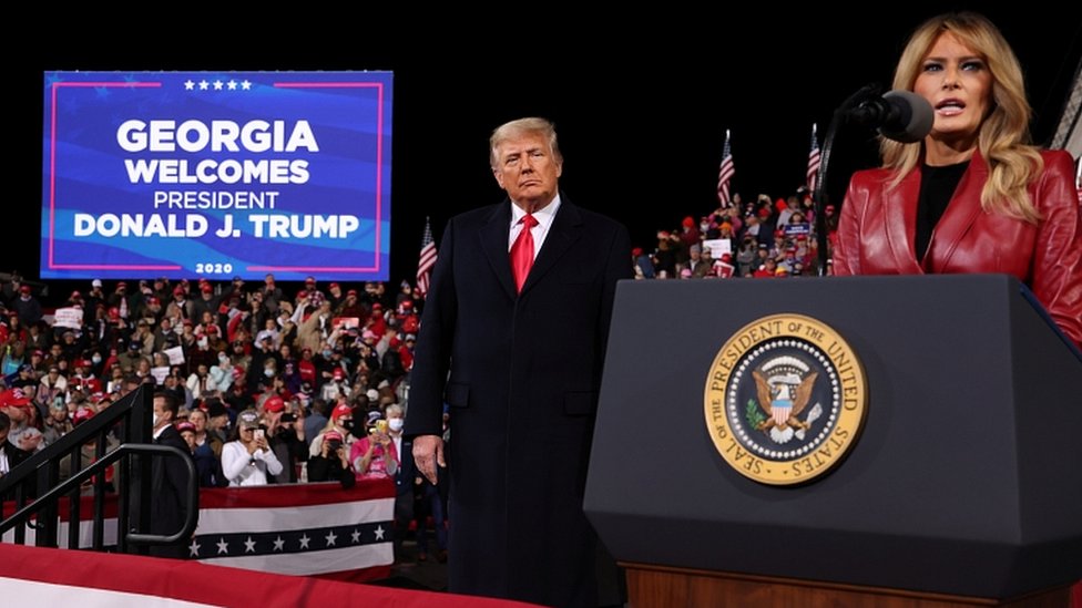 US President Donald Trump listens as first lady Melania Trump at a campaign rally in Valdosta, Georgia