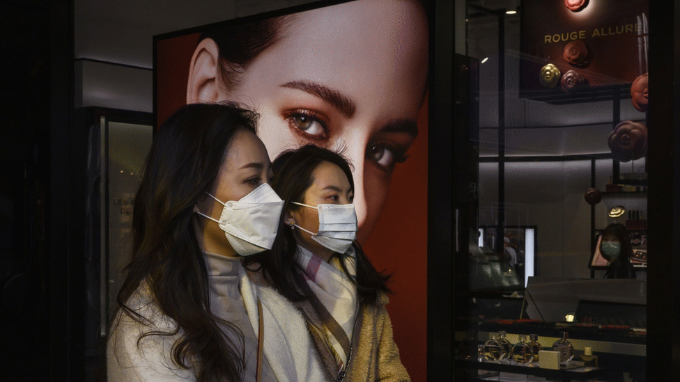 兩名婦女在北京三里屯購物時路過一家奢侈品店時戴著防護口罩。