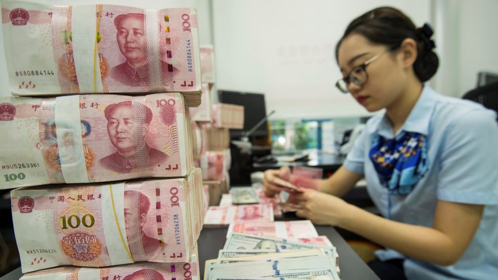 Mujer contabilizando yuanes y dólares.