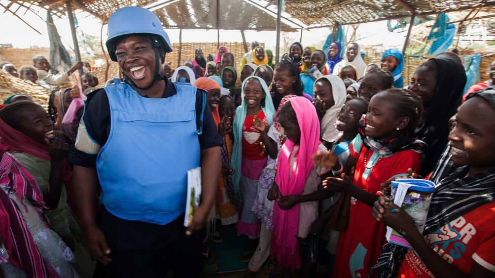 Женщина-полицейский ООН из Ганы с детьми-беженцами в Дарфуре, Судан, май 2014 г.