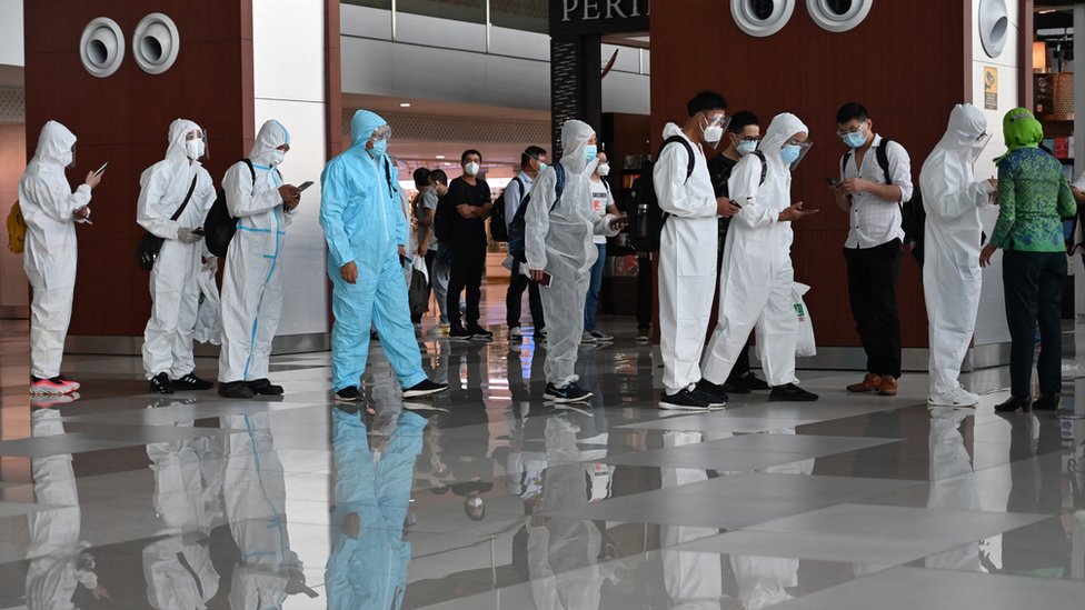 印尼雅加達蘇加諾—哈達國際機場一批身穿醫療防護衣的中國旅客凖備登機飛往深圳（8/6/2021）