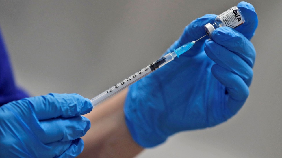 Medic drawing vaccine through a syringe