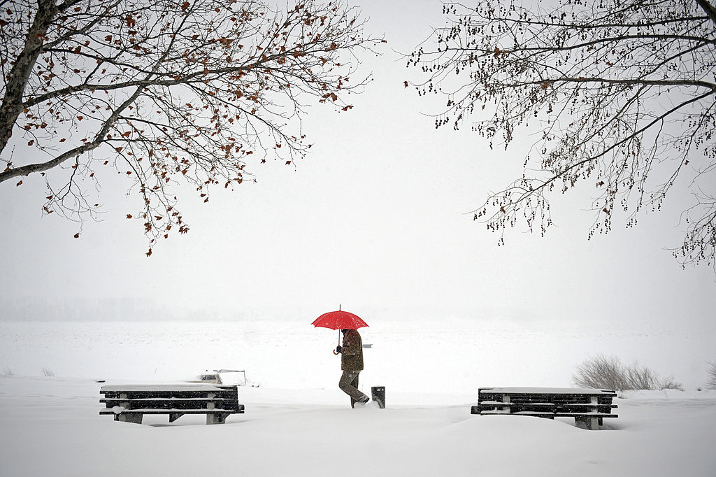 Homem caminha sobre a neve às margens do rio Danúbio, em Belgrado