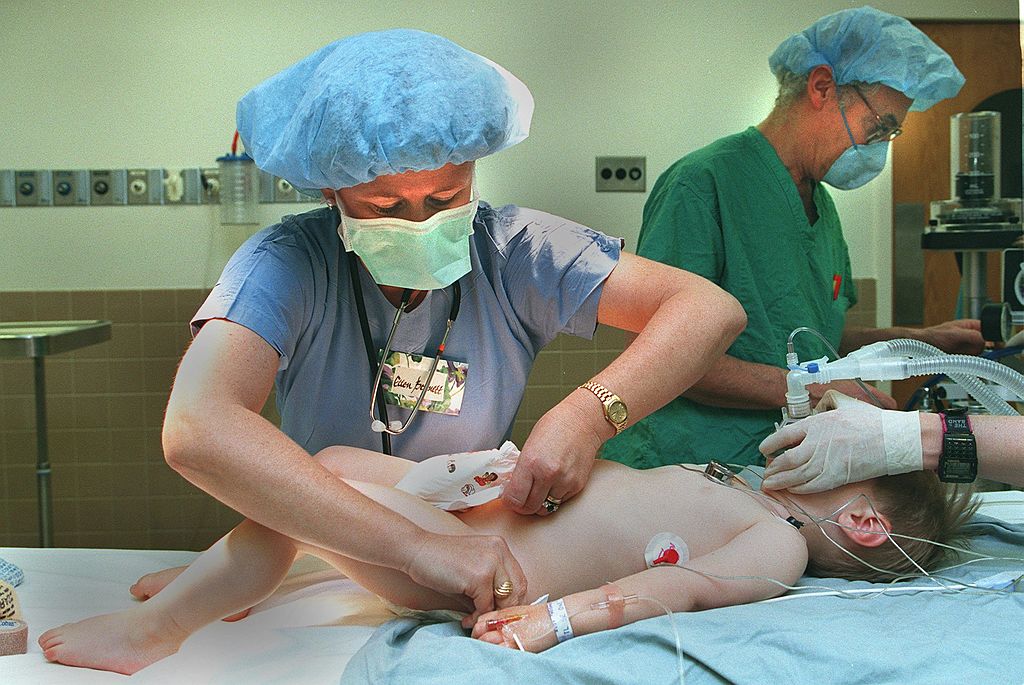 Enfermera atiende a un niño circuncidado en un quirófano.