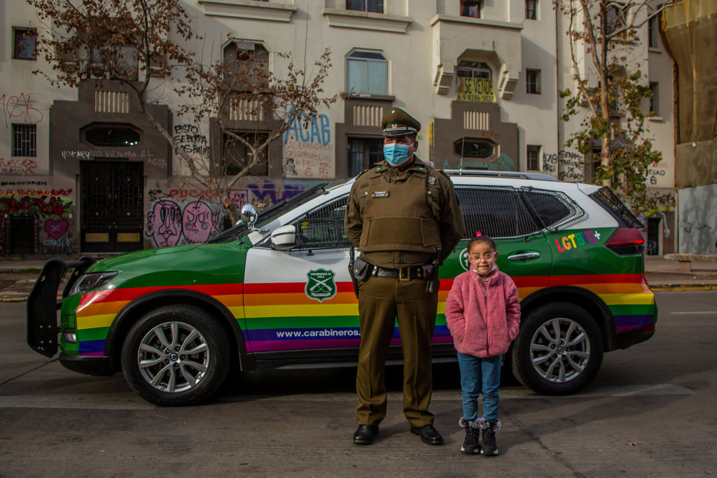 Niña posando con un policía en una marcha gay. 