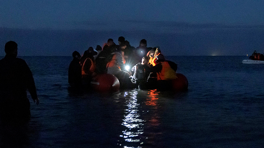 Migrants prepare to cross the Channel towards England on an inflatable boat at night near Wimereux, northern France, 16 October 2021