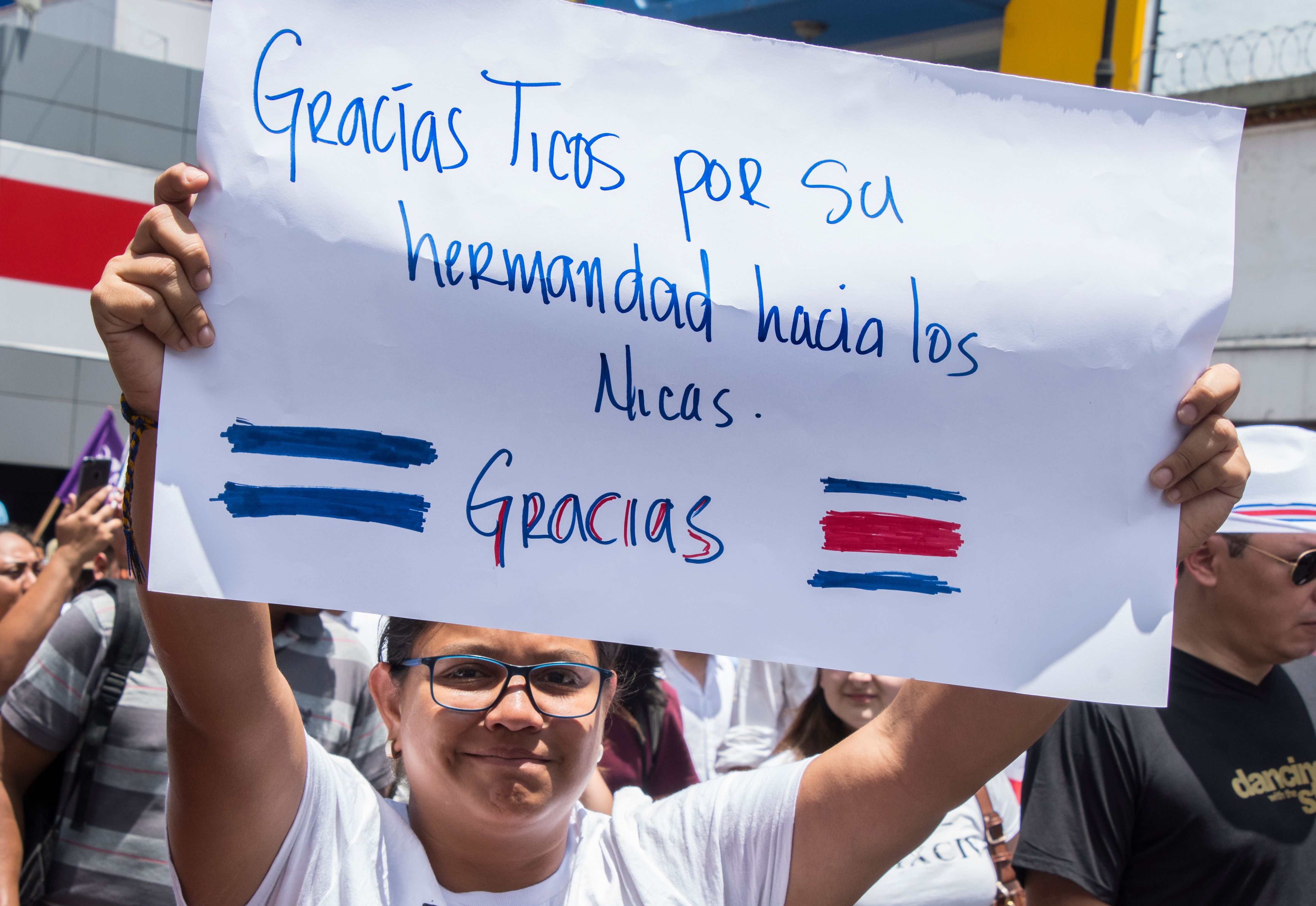 A woman holds up a sign reading "Thanks Ticos [Costa Ricans] for your brotherhood towards the Nicaraguans, thanks. 