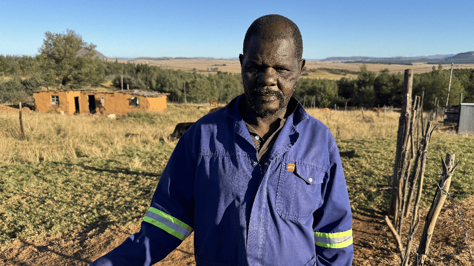 A farm worker in a blue overall looking at the camera