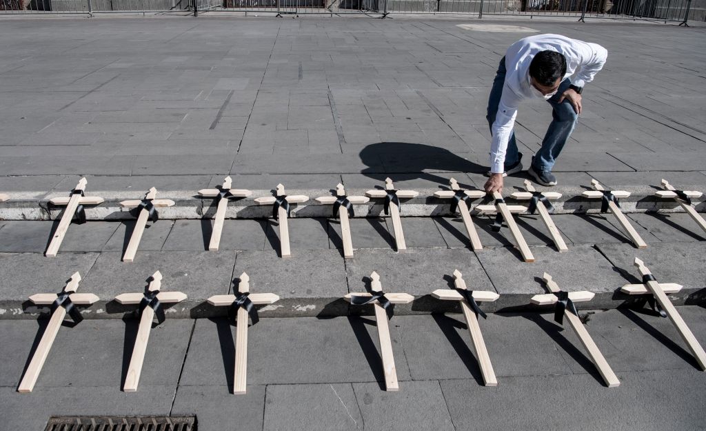 Un hombre coloca cruces frente a la Catedral de Santiago en conmemoración de las víctimas de covid