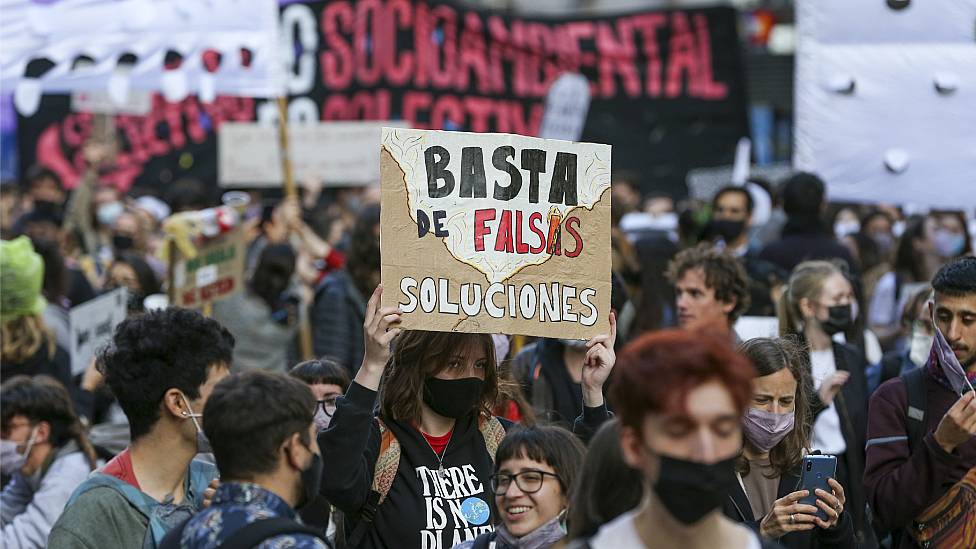 Climate protest in Latin America. A girl holds a banner that says "No more false solutions"