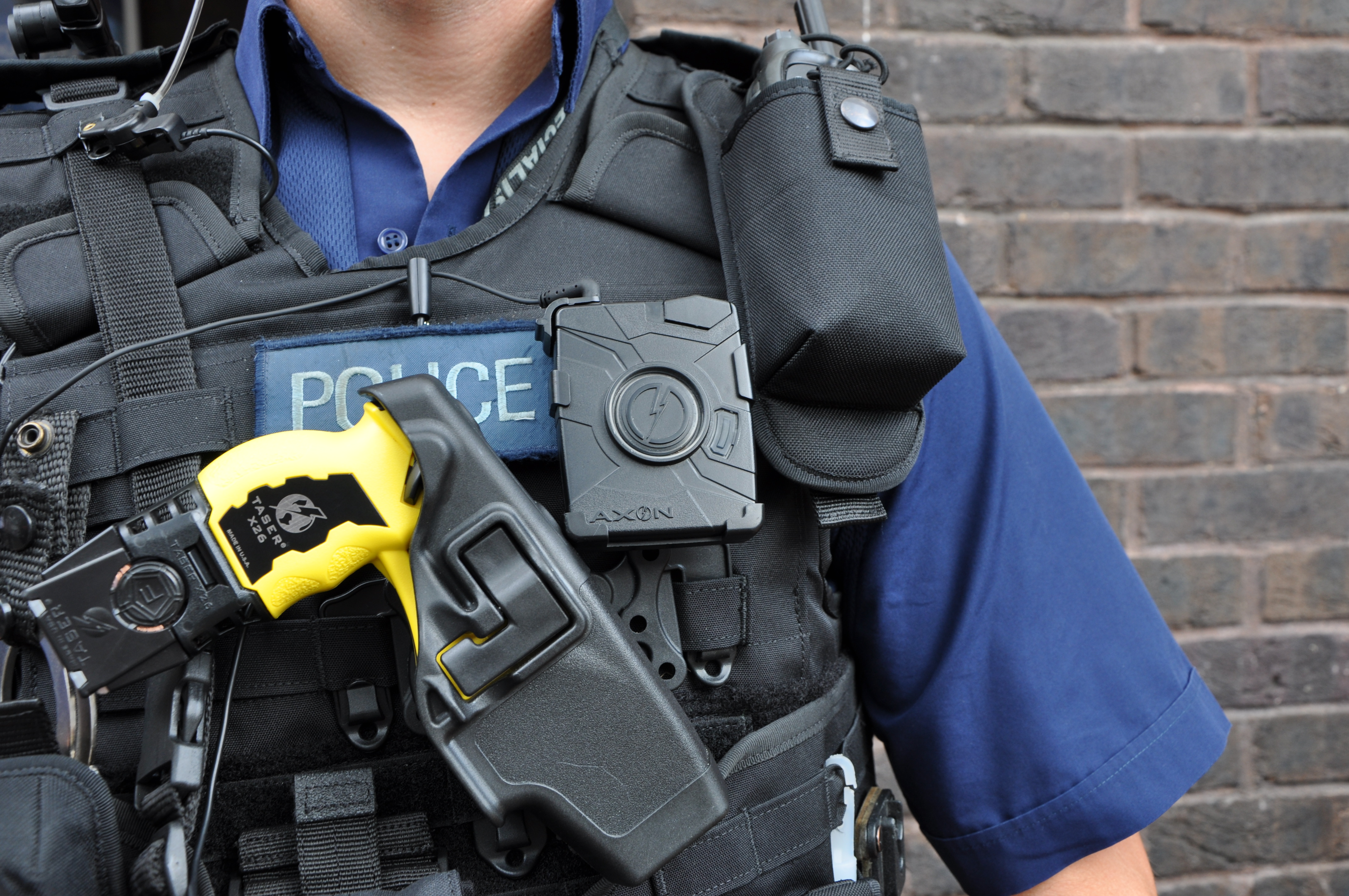 Armed British Police officer, with taser, wearing a body-worn video camera during operational trials